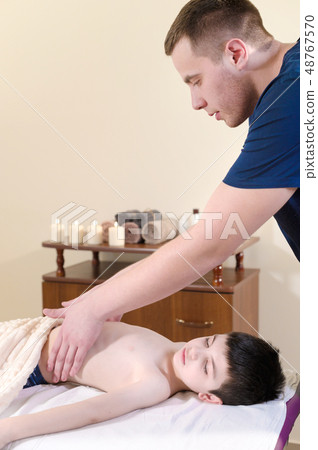 A little boy at the reception at a professional masseuse. Male manual worker gives massage to the 48767570