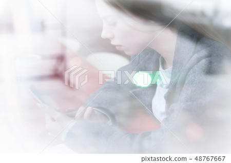 Portrait of a young girl sitting in a cafe outside the window with a reflection of the street Portrait of a young girl sitting in a cafe outside the window with a reflection of the street 48767667