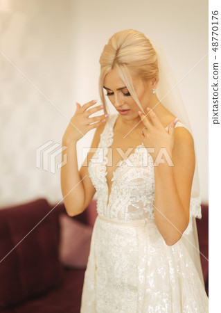 Young and beautiful bride at home. Blond hair girl in wedding dress 48770176