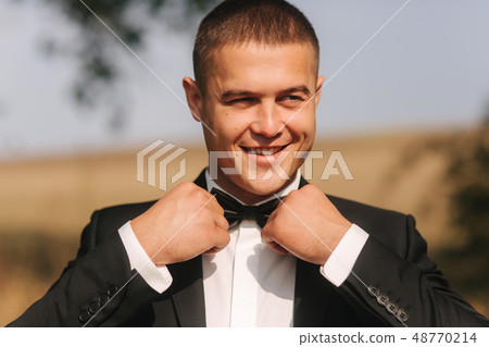 Handsome groomm dressed a tie bow. Wedding day. Man outside Handsome groomm dressed a tie bow. Wedding day. Man outside 48770214