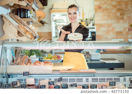 Salesgirl selling cheese in deli or supermarket 48773150