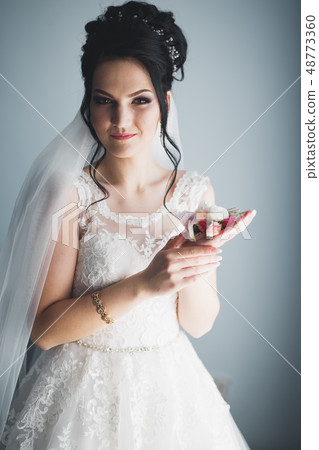 Gorgeous bride in robe posing and preparing for the wedding ceremony face in a room Gorgeous bride in robe posing and preparing for the wedding ceremony face in a room 48773360