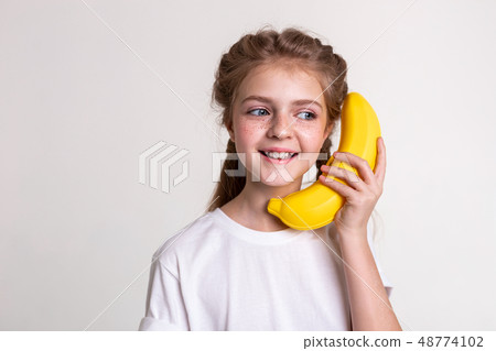 Joyful long-haired child with blue eyes carrying plastic banana Joyful long-haired child with blue eyes carrying plastic banana 48774102