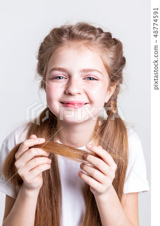 Joyful beaming little girl carrying ends of her long hair Joyful beaming little girl carrying ends of her long hair 48774591