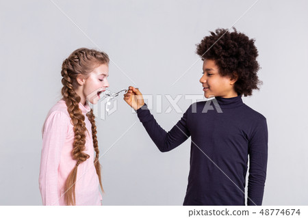 Resolute boy with wild hair feeding his girlfriend with headphones 48774674