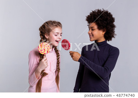 Smiling African American dark-haired boy proposing his red candy 48774740