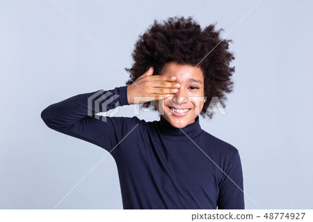 Smiling curly positive child closing one eye with hand Smiling curly positive child closing one eye with hand 48774927