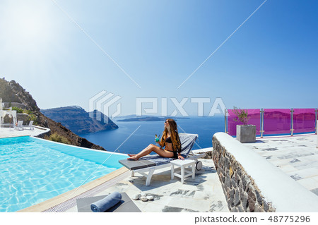 Woman with a drink by the pool 48775296