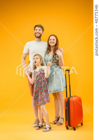 Happy parent with daughter and suitcase at studio isolated on yellow background Happy parent with daughter and suitcase at studio isolated on yellow background 48775346