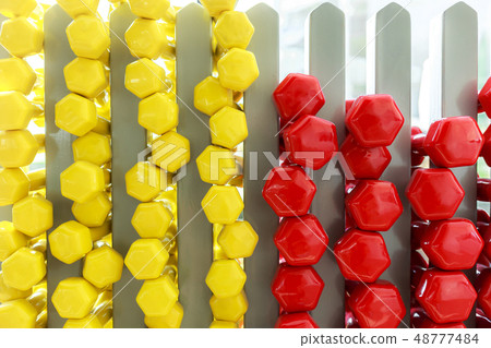 A lot of colorful dumbbell on stand 48777484