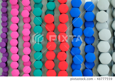 A lot of colorful dumbbell on stand 48777559