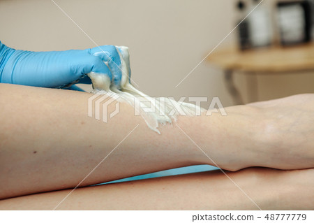 Epilation wax in the spa salon. Beautician imposes wax on women's legs. Close-up. Epilation wax in the spa salon. Beautician imposes wax on women's legs. Close-up. 48777779