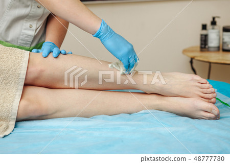 Epilation wax in the spa salon. Beautician imposes wax on women's legs. Close-up. Epilation wax in the spa salon. Beautician imposes wax on women's legs. Close-up. 48777780