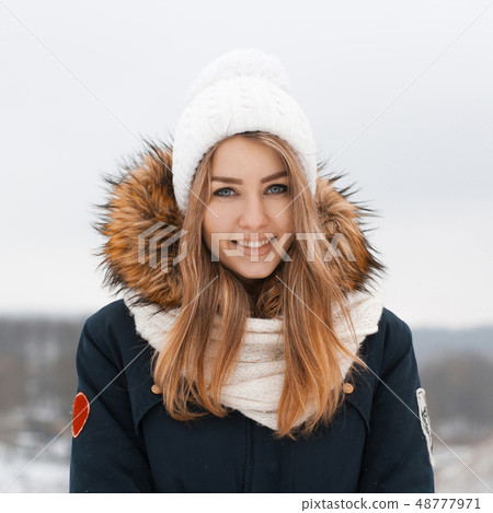 Sweet girl in a knitted hat and jacket smiles. Sweet girl in a knitted hat and jacket smiles. 48777971