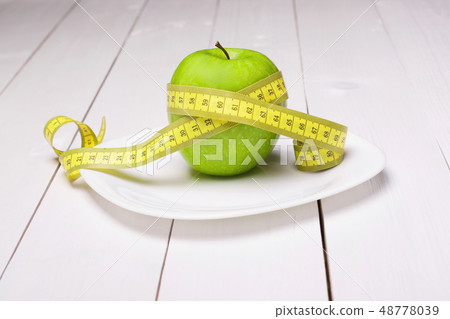 Apple with centimeter on the plate. Healthy eating Apple with centimeter on the plate. Healthy eating 48778039