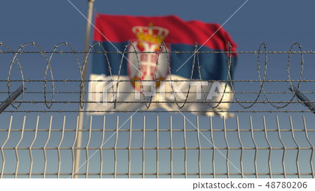 Defocused waving flag of Serbia behind barbed wire fence. 3D rendering 48780206