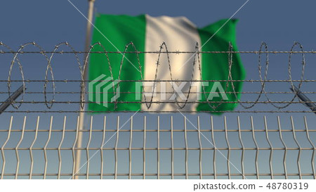 Defocused waving flag of Nigeria behind barbed wire fence. 3D rendering 48780319