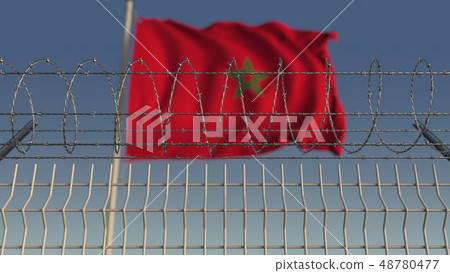 Defocused waving flag of Morocco behind barbed wire fence. 3D rendering Defocused waving flag of Morocco behind barbed wire fence. 3D rendering 48780477