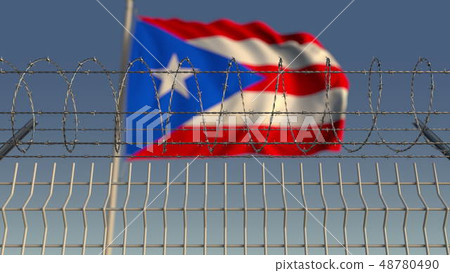 Blurred waving flag of Puerto rico behind barbed wire fence. 3D rendering Blurred waving flag of Puerto rico behind barbed wire fence. 3D rendering 48780490