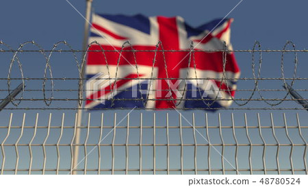 Defocused waving flag of Great Britain behind barbed wire fence. 3D rendering 48780524