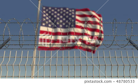 Defocused waving flag of the United States behind barbed wire fence. 3D rendering 48780533