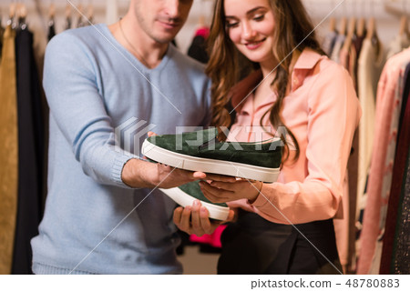 Close-up of hands holding dark green moccasins. Close-up of hands holding dark green moccasins. 48780883