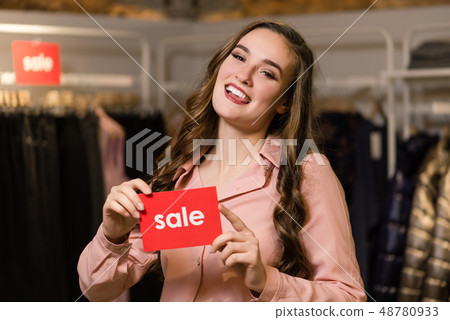 Brunette woman holds red sign with sale word. 48780933