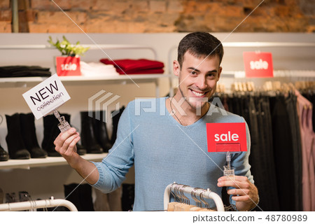 Young man with red sale and white new collection tags. Young man with red sale and white new collection tags. 48780989