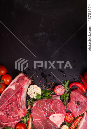 Raw meat steaks on a dark background ready to roasting Raw meat steaks on a dark background ready to roasting 48781494
