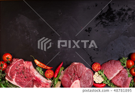 Raw meat steaks on a dark background ready to roasting Raw meat steaks on a dark background ready to roasting 48781895