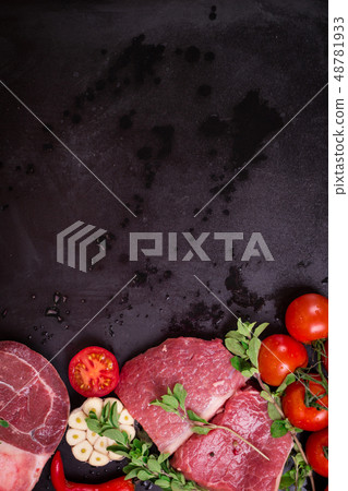 Raw meat steaks on a dark background ready to roasting Raw meat steaks on a dark background ready to roasting 48781933