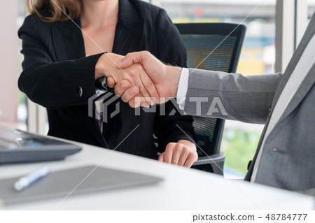 Businessman handshake businesswoman in office. 48784777