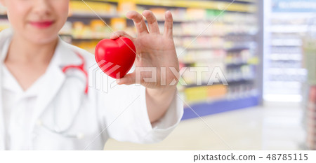 Doctor holding a red heart at hospital office. Doctor holding a red heart at hospital office. 48785115