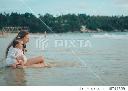 Mother with her child sitting on the sand beside the sea. 8 march 48794869