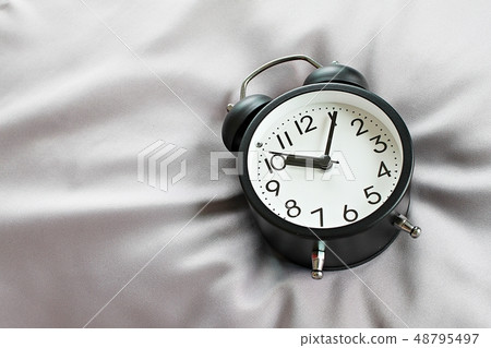 Black retro alarm clock on bed 48795497