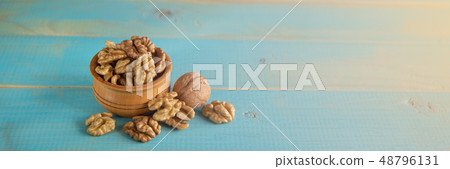 Walnuts on blue rustic table in wooden bowl Walnuts on blue rustic table in wooden bowl 48796131