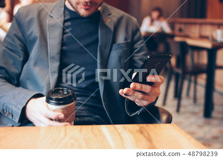Adult man drinking coffee from paper cup and using Adult man drinking coffee from paper cup and using 48798239