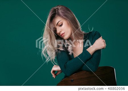 blonde woman posing in green dress on green background 48802036