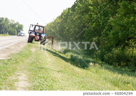 Tractors machines mowing lawn grass along road Tractors machines mowing lawn grass along road 48804294