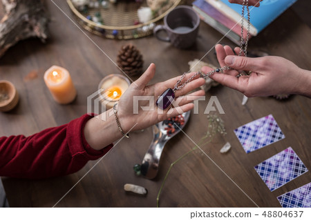 Top view of a female hand taking the necklace 48804637