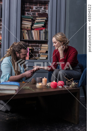 Joyful good looking woman sitting in front of the chiromancer 48804822