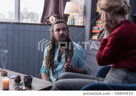 Serious bearded fortune teller looking at his client 48804919