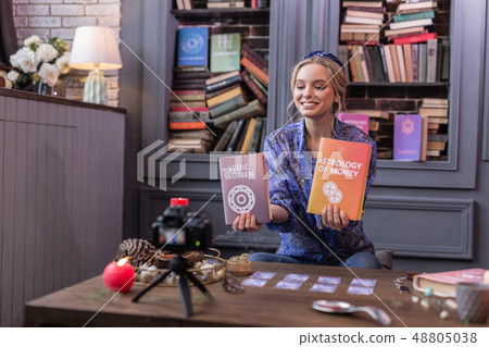 Positive joyful young woman holding two books Positive joyful young woman holding two books 48805038