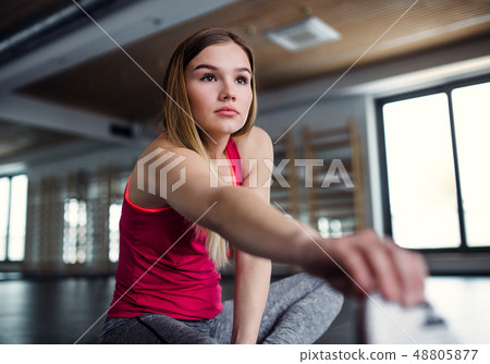 A portrait of young girl or woman doing exercise in a gym. 48805877