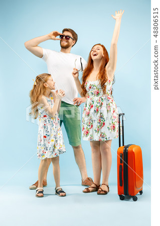Happy parent with daughter and suitcase at studio isolated on blue background Happy parent with daughter and suitcase at studio isolated on blue background 48806515