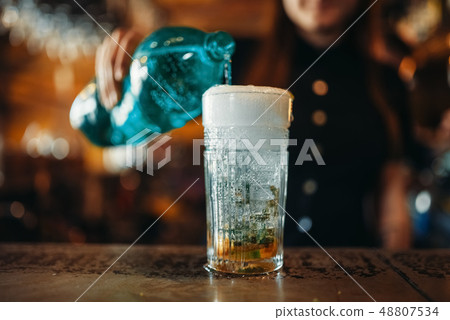 Female barman pours aerated water into a glass Female barman pours aerated water into a glass 48807534