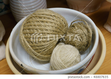 The balls of thread are in the bowl. 48807635
