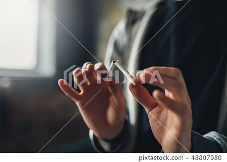 Addicted male person breaks a cigarette Addicted male person breaks a cigarette 48807980