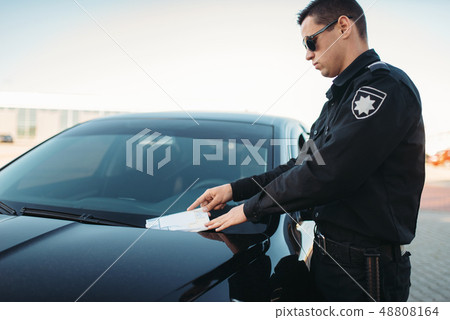 Male policeman in uniform writes a fine on road Male policeman in uniform writes a fine on road 48808164