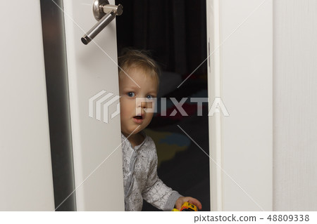 Kid peeking out of the open room door. Surprised face expression 48809338